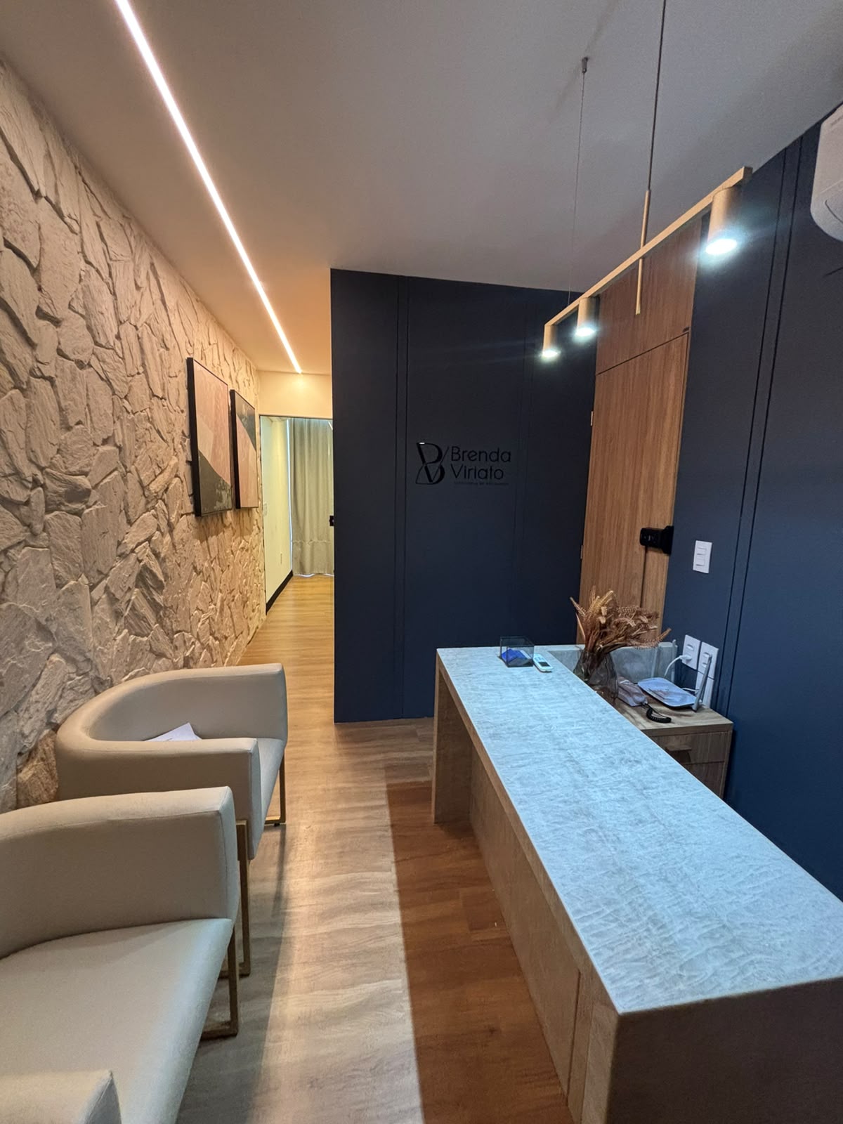 Recepção do escritório, com painel azul e a identidade Brenda Viriato aplicada na parede.