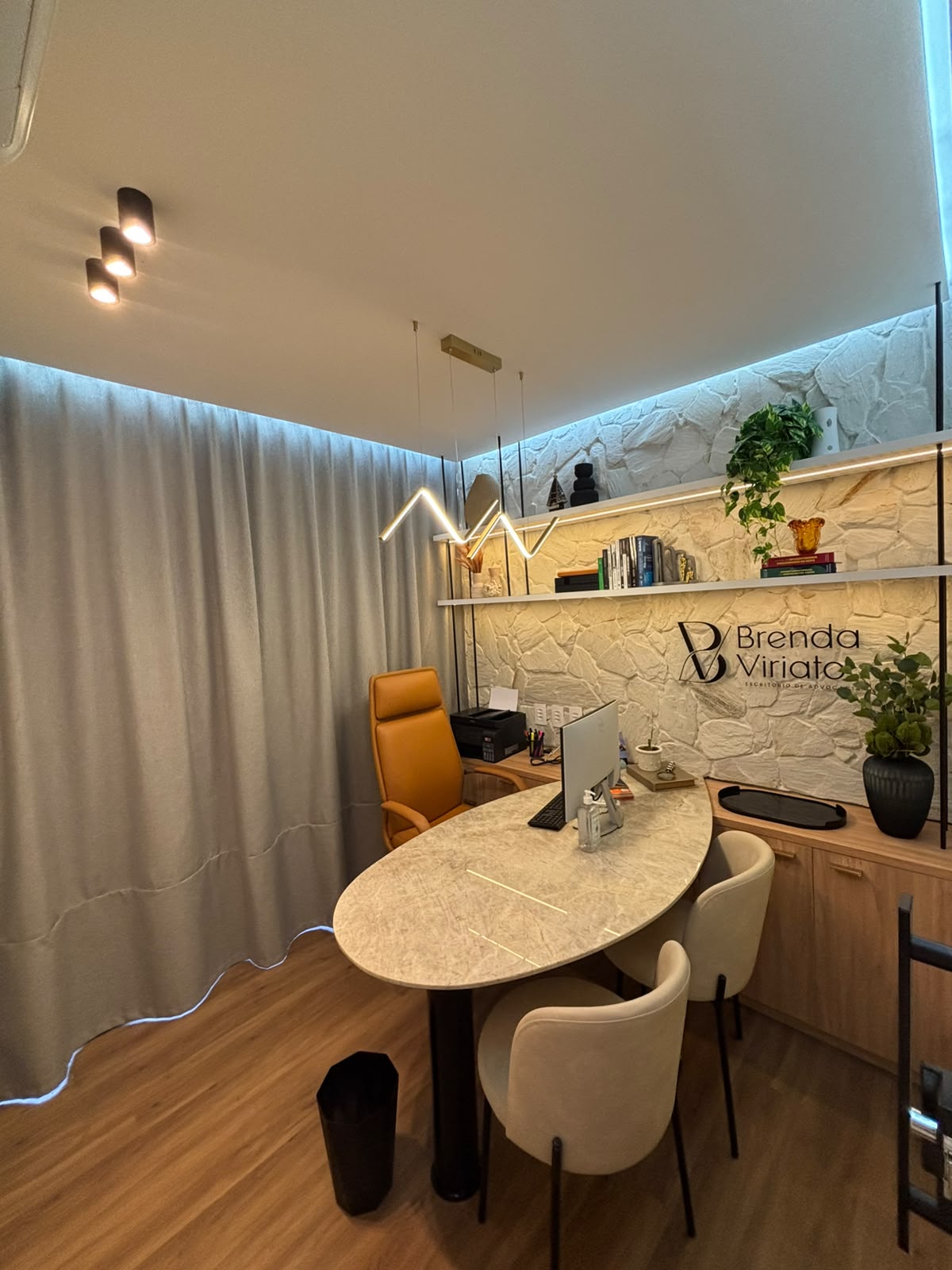 Vista ampla da sala de reuniões, com iluminação suave e assentos para acompanhantes.